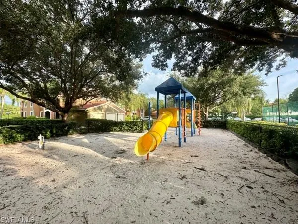a view of a playground with a slide and a tree
