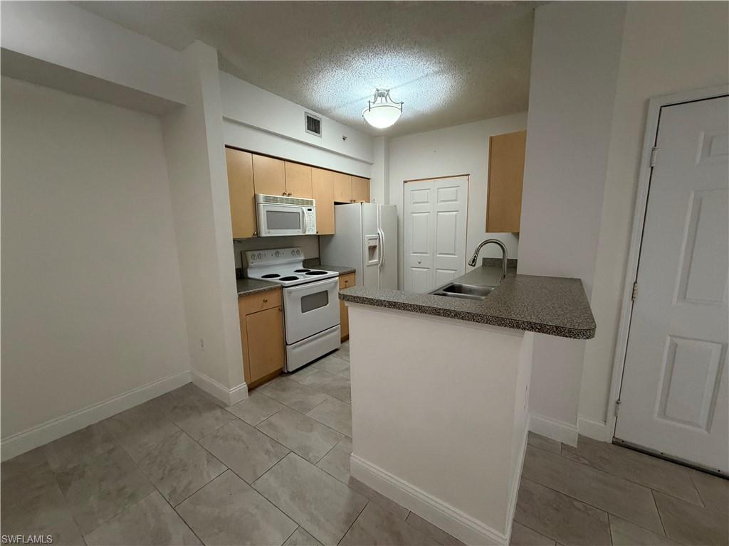 1210 Reserve Way, Unit 9107 Naples, FL 34105 - Photo 8 of 22 a kitchen with stainless steel appliances granite countertop a sink stove and refrigerator