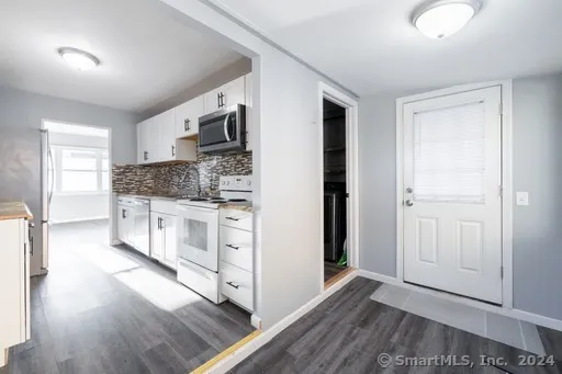 a large white kitchen with stainless steel appliances granite countertop a stove and a refrigerator