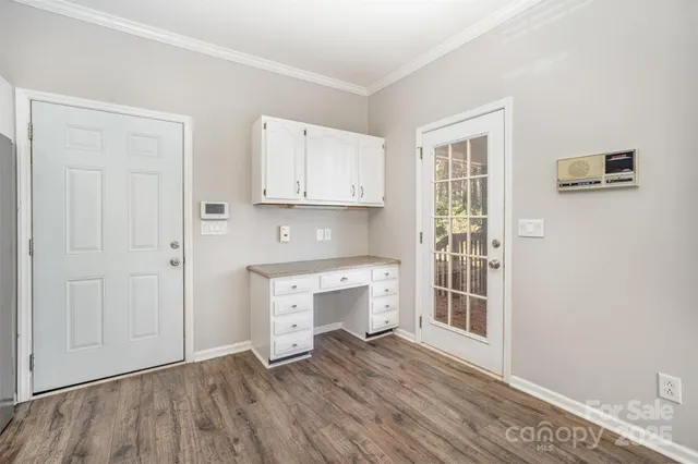 an empty room with wooden floor cabinet and a window