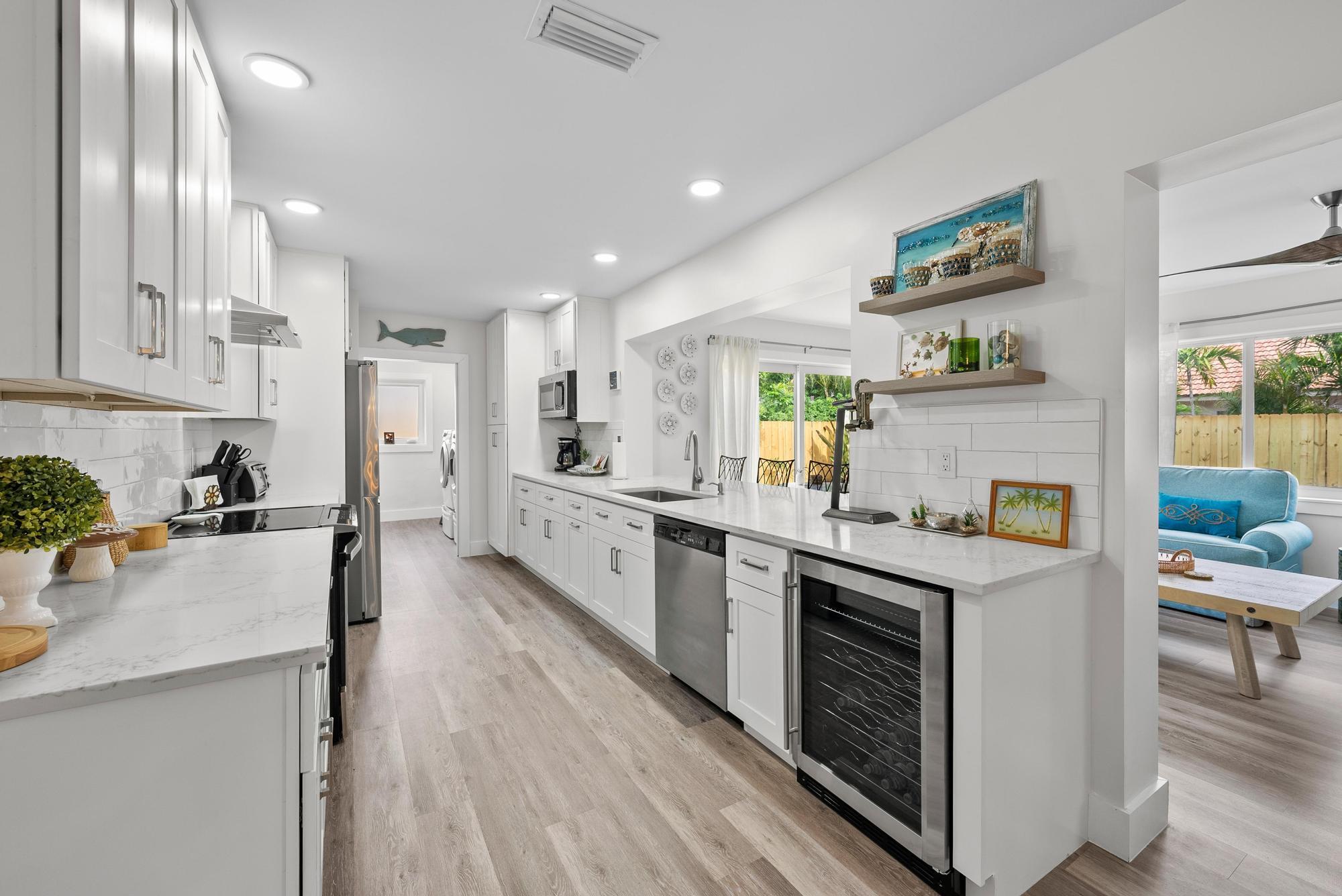 517 Gulf Road North Palm Beach, FL 33408 - Photo 14 of 59 a kitchen with stainless steel appliances granite countertop a stove top oven a sink a refrigerator and white cabinets with wooden floor