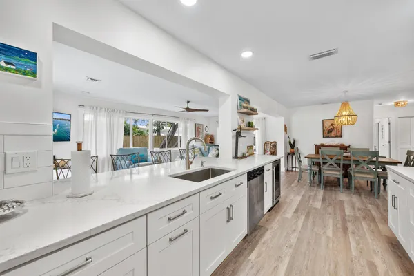 a kitchen with stainless steel appliances granite countertop a stove top oven a sink a refrigerator and white cabinets with wooden floor