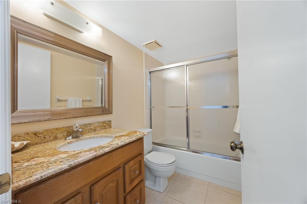 5683 Rattlesnake Hammock Road, Unit A202 Naples, FL 34113 - Photo 20 of 27 Full bathroom featuring shower / bath combination with granite countertop, glass door, vanity, and light tile patterned floors