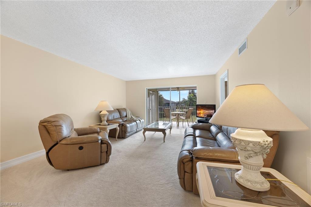 5683 Rattlesnake Hammock Road, Unit A202 Naples, FL 34113 - Photo 7 of 27 Living area with light carpet and a textured ceiling