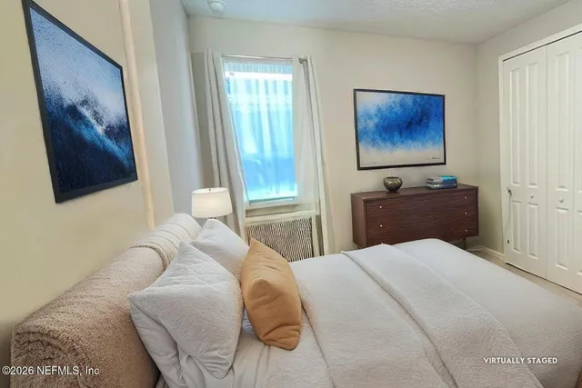 a bedroom with a bed and a flat tv screen on dresser