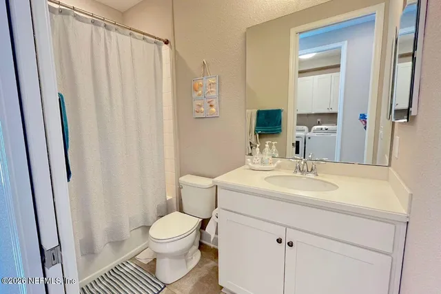 a bathroom with a sink a toilet a mirror and shower curtain