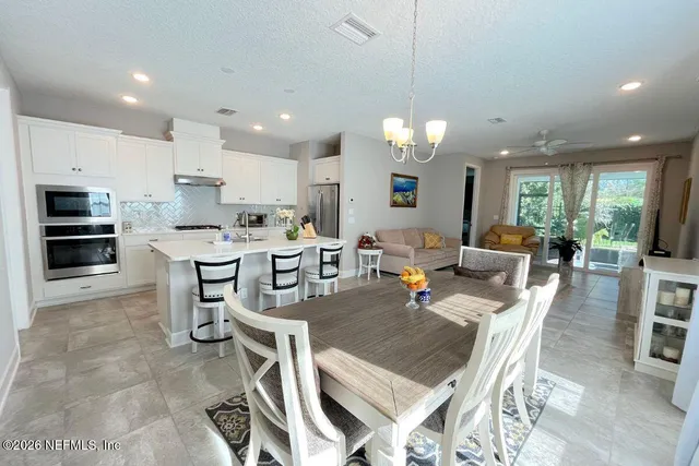 a living room with stainless steel appliances furniture a dining table and chairs