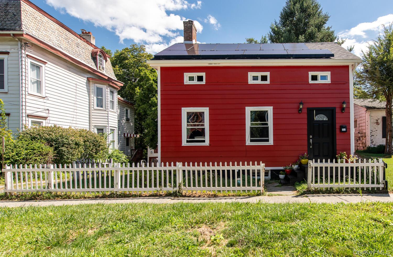 88 South Hamilton Street Poughkeepsie, NY 12601 - Photo 3 of 47 View of front facade with roof mounted solar panels, a chimney, and a fenced front yard