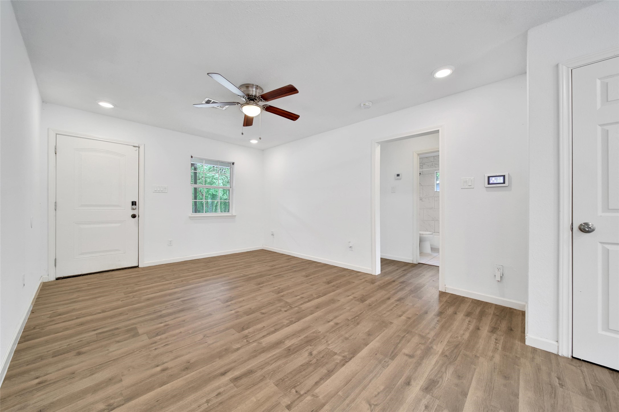 7346 Calais Road Houston, TX 77033 - Photo 2 of 9 an empty room with wooden floor ceiling fan and windows