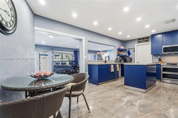 a kitchen with stainless steel appliances granite countertop a stove top oven a sink dishwasher a dining table and chairs with wooden floor