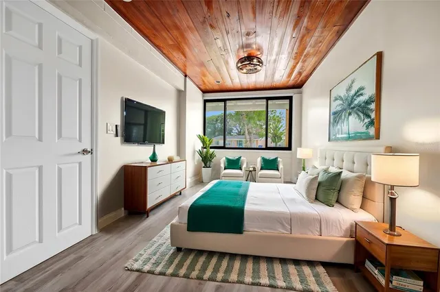 a bedroom with a large bed a flat tv screen and a dresser