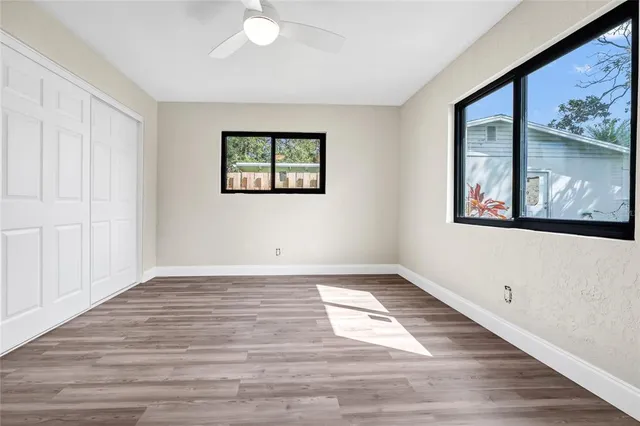 a view of an empty room with wooden floor and a window