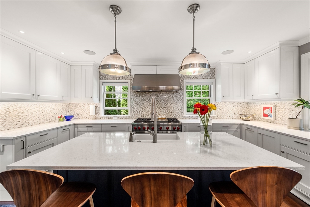 53 Crowninshield Road Brookline, MA 02446 - Photo 10 of 42 a kitchen with stainless steel appliances a dining table chairs and white cabinets