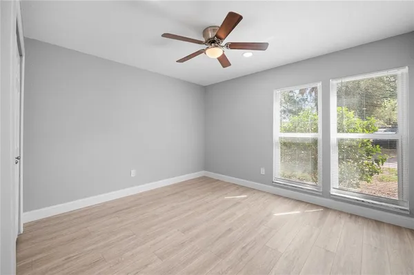 an empty room with wooden floor and windows