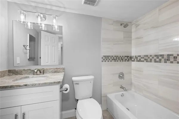 a bathroom with a granite countertop sink a toilet and bathtub