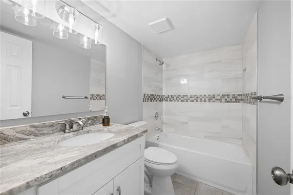 a bathroom with a granite countertop sink a toilet and bathtub