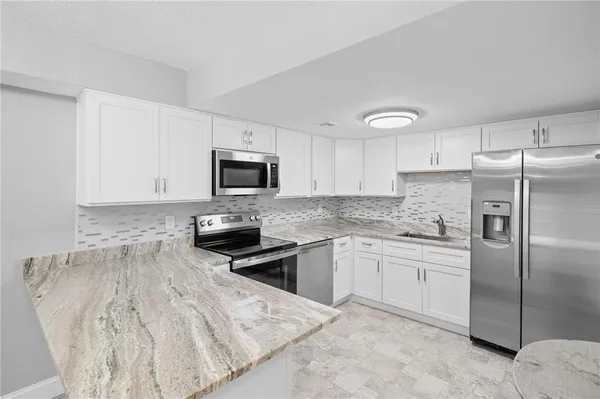 a kitchen with granite countertop a refrigerator sink and microwave