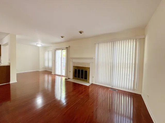 a view of a livingroom with wooden floor fireplace and window