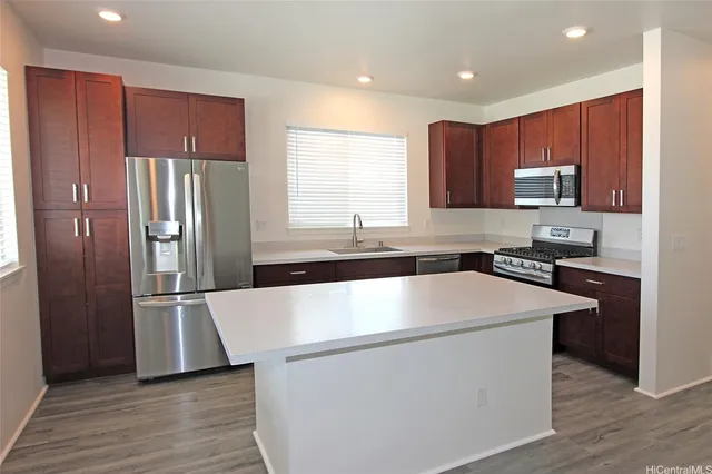 a kitchen with stainless steel appliances granite countertop a refrigerator a sink a stove and a microwave oven on the wooden floor