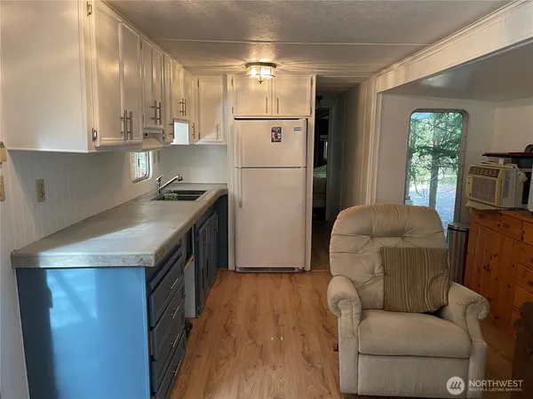 a kitchen with kitchen island a white cabinets a sink a refrigerator and wooden floors