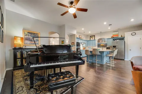 a kitchen with stainless steel appliances granite countertop a stove top oven a sink a dining table and chairs with wooden floor