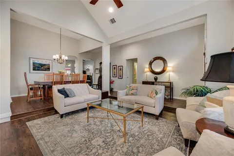 a living room with furniture kitchen view and a chandelier
