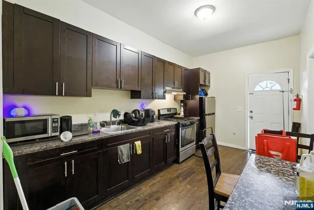 a kitchen with granite countertop a sink cabinets and stainless steel appliances