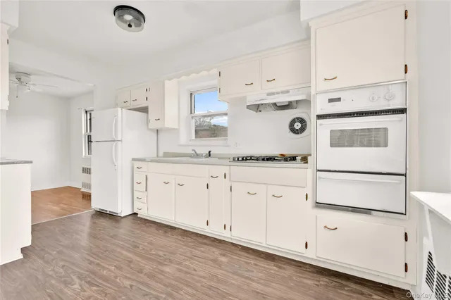 a kitchen with stainless steel appliances white cabinets and wooden floors