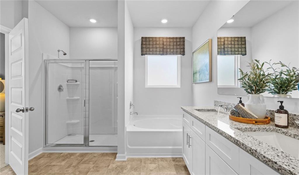205 Storm Lane Hoschton, GA 30548 - Photo 26 of 51 a bathroom with a granite countertop sink a mirror a bathtub and shower