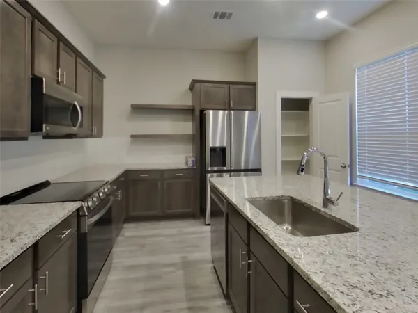 a kitchen with stainless steel appliances granite countertop a sink a stove and a refrigerator