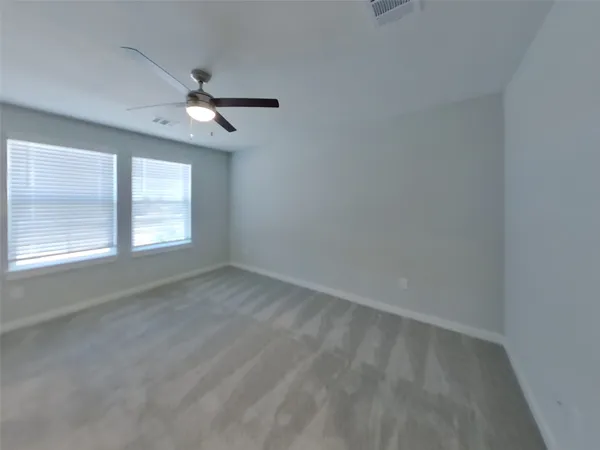 an empty room with a window and ceiling fan