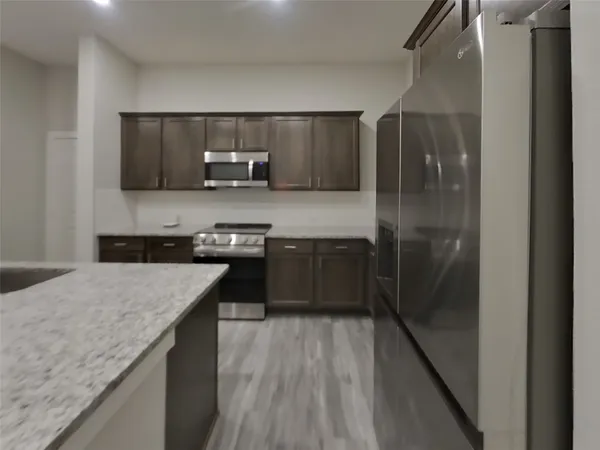 a kitchen with stainless steel appliances granite countertop a refrigerator a sink and a stove