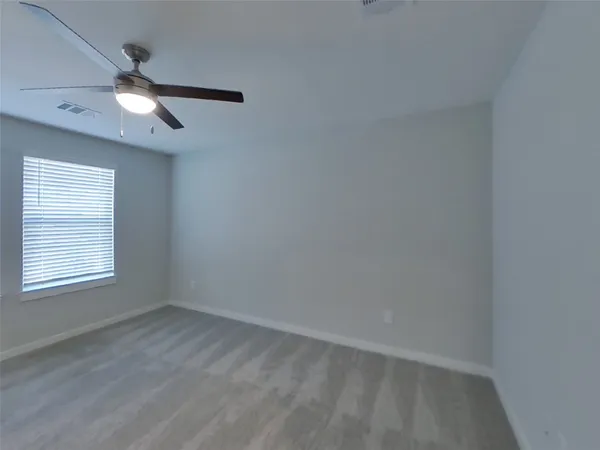 an empty room with a window and a fan