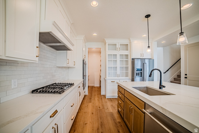 223 South Cottonwood Road, Unit 7501 Vineyard, UT 84059 - Photo 41 of 45 Kitchen featuring white shaker cabinetry, light wood-finish flooring, white countertops, stainless steel appliances, and a central island with an undermount sink