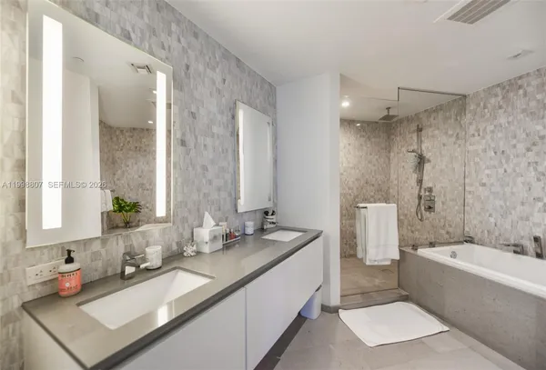 a bathroom with a granite countertop sink mirror and a bath tub