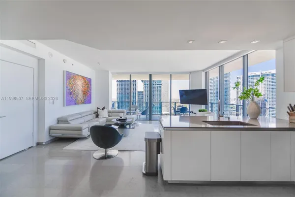 a living room with furniture a large window and kitchen view