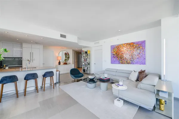 a living room with furniture a table and kitchen view
