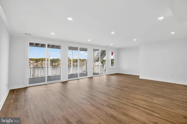 a living room with couches a fireplace and kitchen view with wooden floor