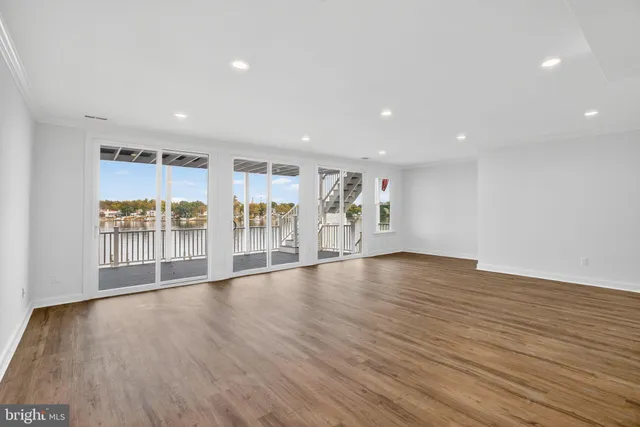 a living room with couches a fireplace and kitchen view with wooden floor