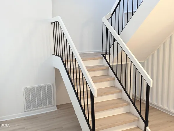 a view of staircase with wooden floor and white walls