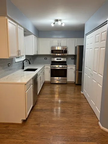 a view of an empty room with wooden floor and a ceiling fan