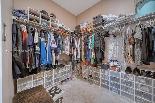 a view of walk in closet with clothes and shoes