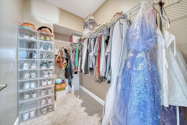 a view of walk in closet with clothes and shoes