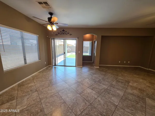 a view of an empty room with window and chandelier fan