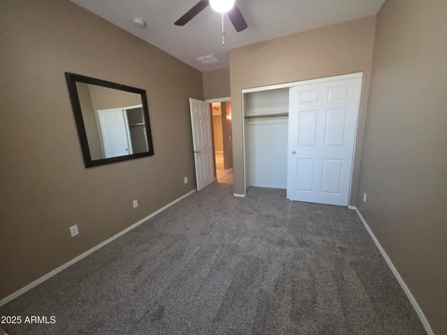 an empty room with closet and a chandelier fan