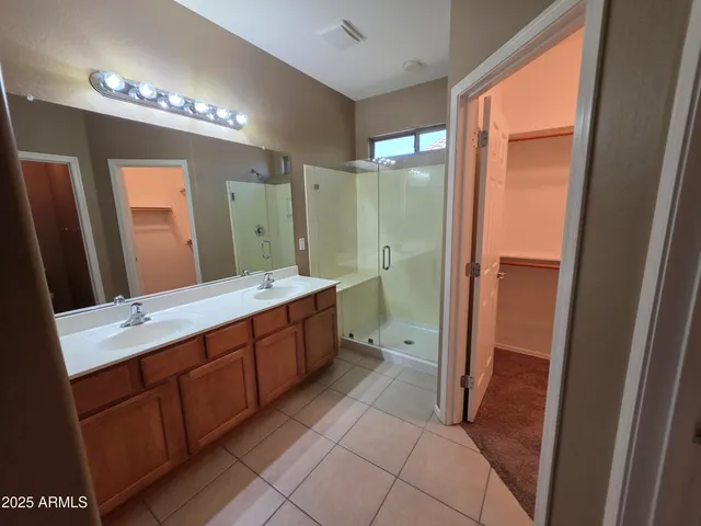 a spacious bathroom with a double vanity sink a large mirror and a shower