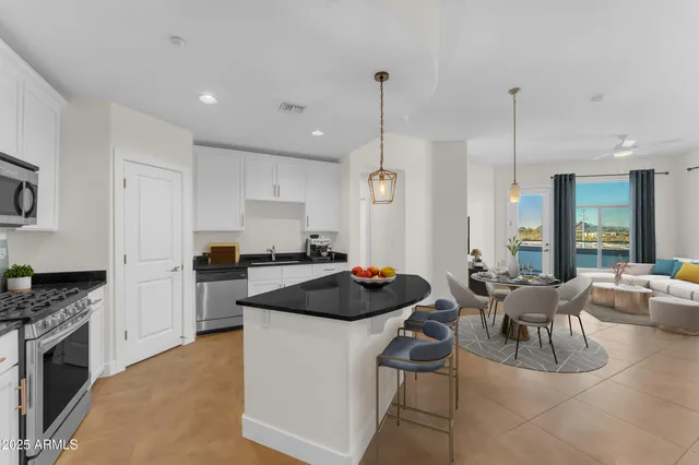 a kitchen with a stove a refrigerator and chairs
