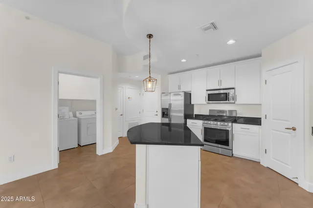 a kitchen with stainless steel appliances granite countertop a sink a stove a refrigerator and white cabinets