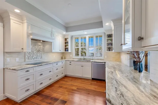 a kitchen with granite countertop a sink and white cabinets