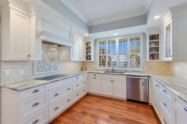 a kitchen with granite countertop a sink white cabinets and dining table with wooden floor
